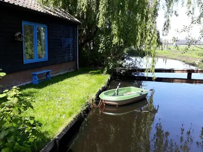 a small boat in the water next to a house at Hortensia Eiland in Zegveld