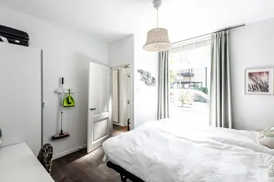 a white bedroom with a bed and a large window at Studio en deluxe appartement Blueberry in Zandvoort