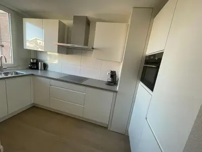 a kitchen with white cabinets and a sink at Appartementen Zeezicht - 7 in Katwijk aan Zee