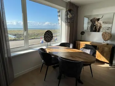 a dining room with a table and a large window at Appartementen Zeezicht - 7 in Katwijk aan Zee