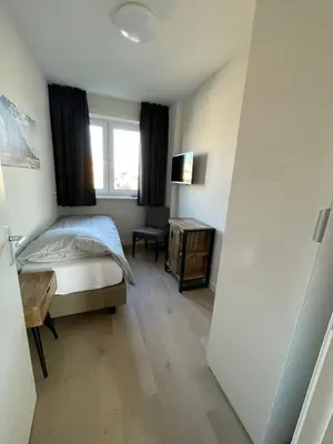 a bedroom with a bed and a desk and a window at Appartementen Zeezicht - 7 in Katwijk aan Zee
