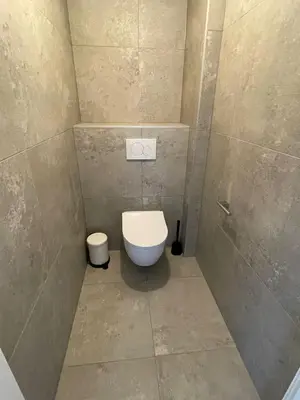 a bathroom with a toilet and a tiled wall at Appartementen Zeezicht - 7 in Katwijk aan Zee