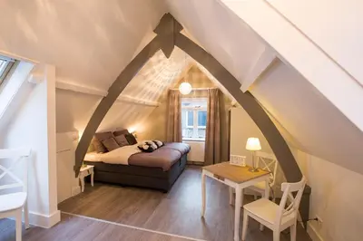 a attic room with a bed and a table at Bed & Breakfast De Vier Seizoenen in Lisse