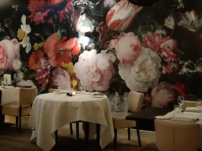 a restaurant with tables and chairs and a floral wall at Bed & Breakfast De Vier Seizoenen in Lisse