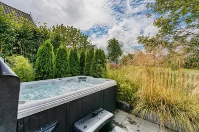 a hot tub in a yard with trees at Appartement YCW 'Papillon' in Rijnsaterwoude