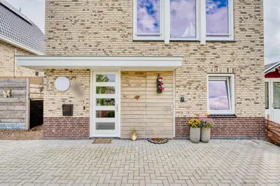 a brick house with a white door and flowers at Appartement YCW 'Papillon' in Rijnsaterwoude