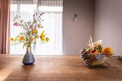 a vase of flowers and a basket of fruit on a table at De Kaasmakerij - Ruim vakantiehuisje op Huize Blokland in Hem