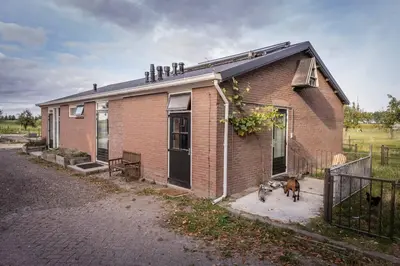 a brick house with two dogs standing outside of it at De Kaasmakerij - Ruim vakantiehuisje op Huize Blokland in Hem