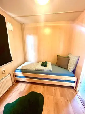a small bed in a small room with a tv at Wellness bungalow with jacuzzi &sauna&private garden near Amsterdam in Vijfhuizen