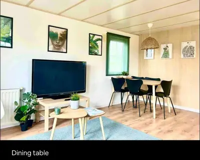 a living room with a television and a dining table at Wellness bungalow with jacuzzi &sauna&private garden near Amsterdam in Vijfhuizen