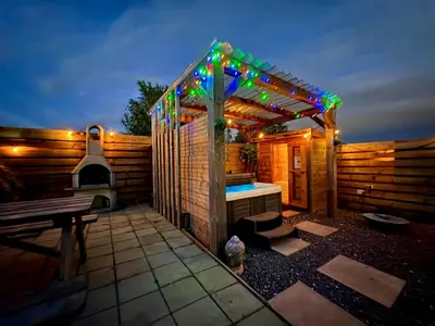 a small backyard with a grill and a wooden fence at Wellness bungalow with jacuzzi &sauna&private garden near Amsterdam in Vijfhuizen