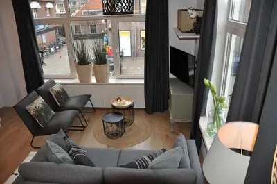 a living room with a couch and chairs and a window at Sunny Reef in Egmond aan Zee