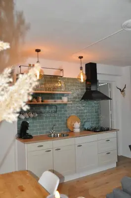 a kitchen with white cabinets and a brick wall at Sunny Reef in Egmond aan Zee