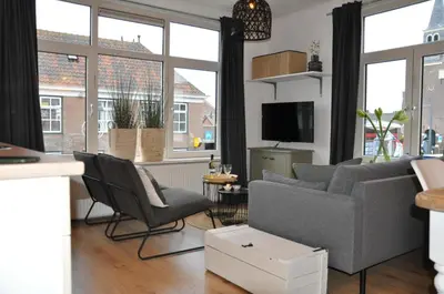 a living room with a couch and chairs and windows at Sunny Reef in Egmond aan Zee
