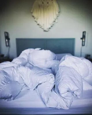 an unmade bed with white sheets and pillows at Bed & Breakfast [H]eerlijk! in De Kwakel