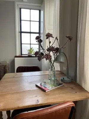 a wooden table with a vase of flowers on it at Bed & Breakfast [H]eerlijk! in De Kwakel