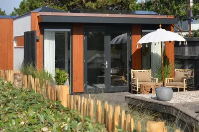 a house with an umbrella and chairs in front of it at Olive Beach, luxury beachhouse 150 m from the beach in Noordwijk aan Zee