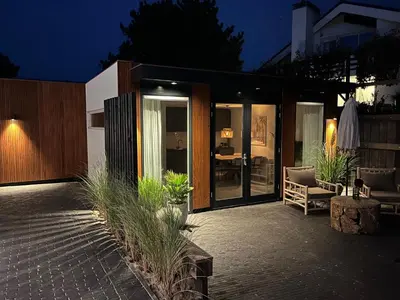 a house with glass doors and a patio at night at Olive Beach, luxury beachhouse 150 m from the beach in Noordwijk aan Zee