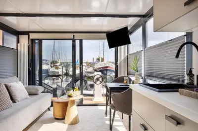 a kitchen and living room with a view of a marina at Cosy tiny houseboats near beach and restaurants by Weltevreden Experience in Zeewolde