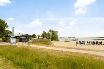 a group of people walking on the beach at Cosy tiny houseboats near beach and restaurants by Weltevreden Experience in Zeewolde