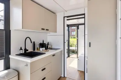 a kitchen with white cabinets and a sink at Cosy tiny houseboats near beach and restaurants by Weltevreden Experience in Zeewolde