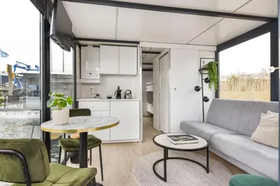 a living room with a couch and a table at Cosy tiny houseboats near beach and restaurants by Weltevreden Experience in Zeewolde