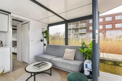 a living room with a couch and a table at Cosy tiny houseboats near beach and restaurants by Weltevreden Experience in Zeewolde
