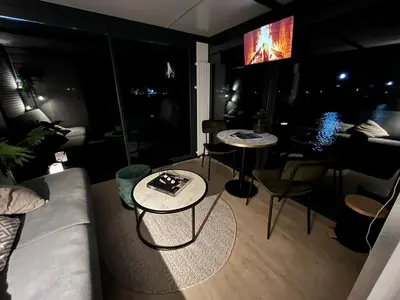 a living room with a couch and tables and a television at Cosy tiny houseboats near beach and restaurants by Weltevreden Experience in Zeewolde