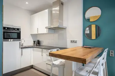 a kitchen with white cabinets and a wooden table at Musea Hotel & Apartments in Amsterdam