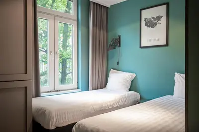 two beds in a room with blue walls and windows at Musea Hotel & Apartments in Amsterdam