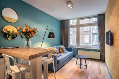 a living room with a table and a blue couch at Musea Hotel & Apartments in Amsterdam