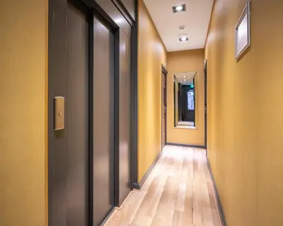 an empty hallway with yellow walls and wooden floors at Musea Hotel & Apartments in Amsterdam