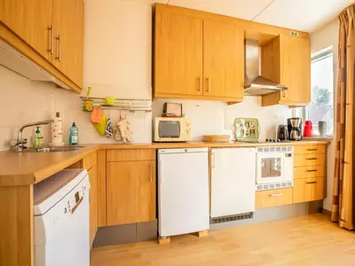 a kitchen with wooden cabinets and a white refrigerator at Comfy holiday home in Hoorn with French balcony in Hoorn