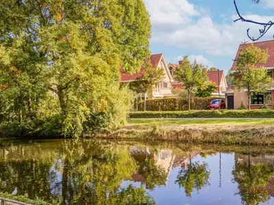 a lake in front of houses with trees at Comfy holiday home in Hoorn with French balcony in Hoorn