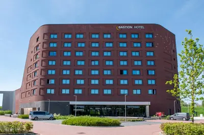 a brown building with cars parked in front of it at Bastion Hotel Amersfoort in Amersfoort