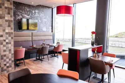 a restaurant with tables and chairs and a large window at Bastion Hotel Amersfoort in Amersfoort