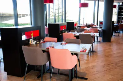 a dining room with tables and chairs and windows at Bastion Hotel Amersfoort in Amersfoort