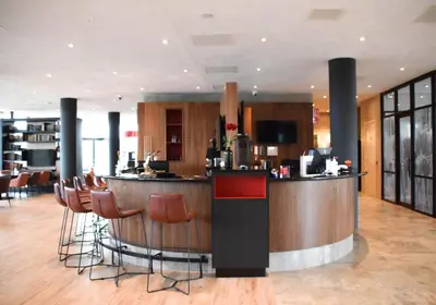 a lobby with a bar with stools around it at Bastion Hotel Amersfoort in Amersfoort