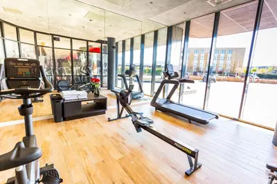 a gym with several treadmills and elliptical machines at Bastion Hotel Amersfoort in Amersfoort