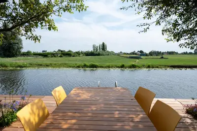 a wooden dock with chairs on a lake at 5 persons Tulpenacker Comfort in Roelofarendsveen