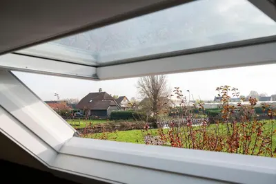 a window with a view of a field and a house at 5 persons Tulpenacker Comfort in Roelofarendsveen