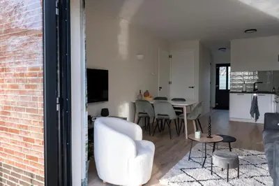 a living room with a white chair and a table at 5 persons Tulpenacker Comfort in Roelofarendsveen