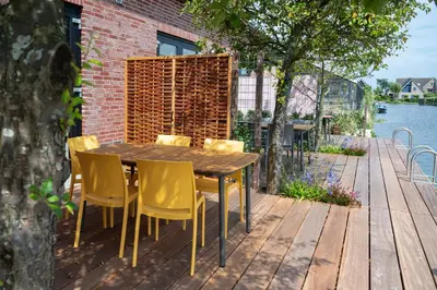 a wooden table and chairs on a deck at 5 persons Tulpenacker Comfort in Roelofarendsveen