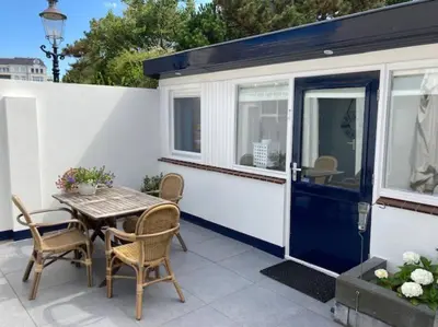 a tiny house with a table and chairs on a patio at Have a nice stay! - Beachhouse Stranddistel 100m from the beach in Noordwijk aan Zee