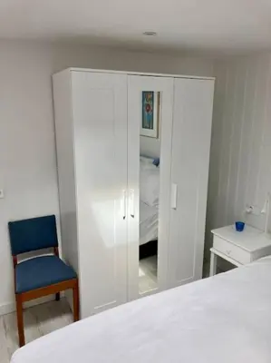a bedroom with a white bed and a blue chair at Have a nice stay! - Beachhouse Stranddistel 100m from the beach in Noordwijk aan Zee