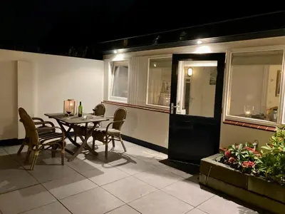 a patio with a table and chairs and a building at Have a nice stay! - Beachhouse Stranddistel 100m from the beach in Noordwijk aan Zee