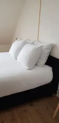 a bed with white pillows on top of it at Vakantiehuis Katwijk in Katwijk