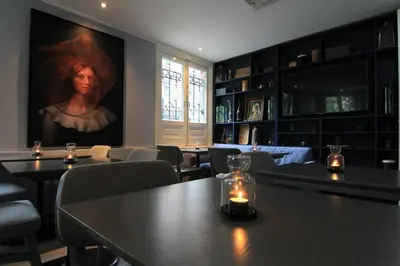 a dining room with tables and a painting of a woman at No. 377 House in Amsterdam