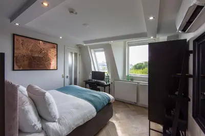 a bedroom with a bed and a desk and windows at No. 377 House in Amsterdam