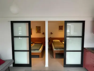 a room with two beds and a room with sliding glass doors at Studio 28A5 with free parking place in Amsterdam